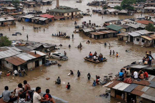 Flooded urban area with people wading and using boats among submerged houses